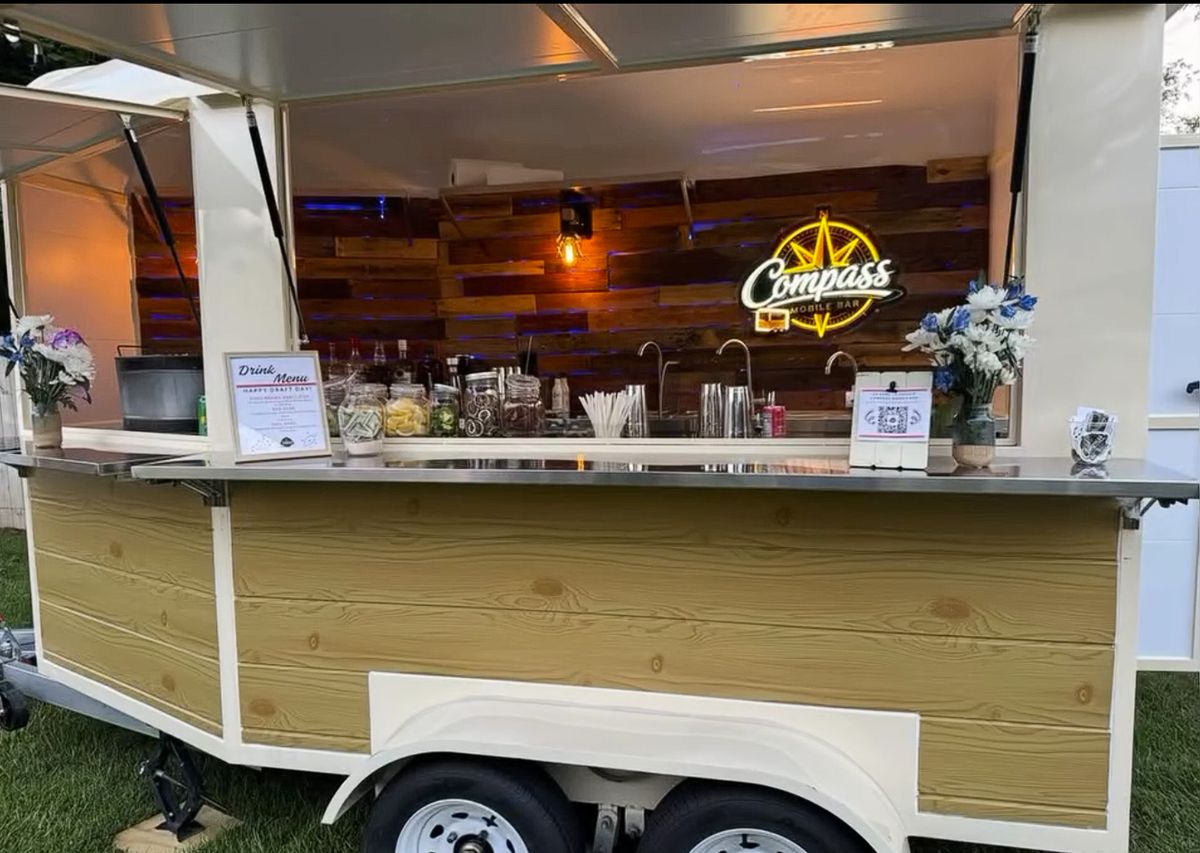 The Compass trailer glowing at dusk with the draft day menu on the bar top