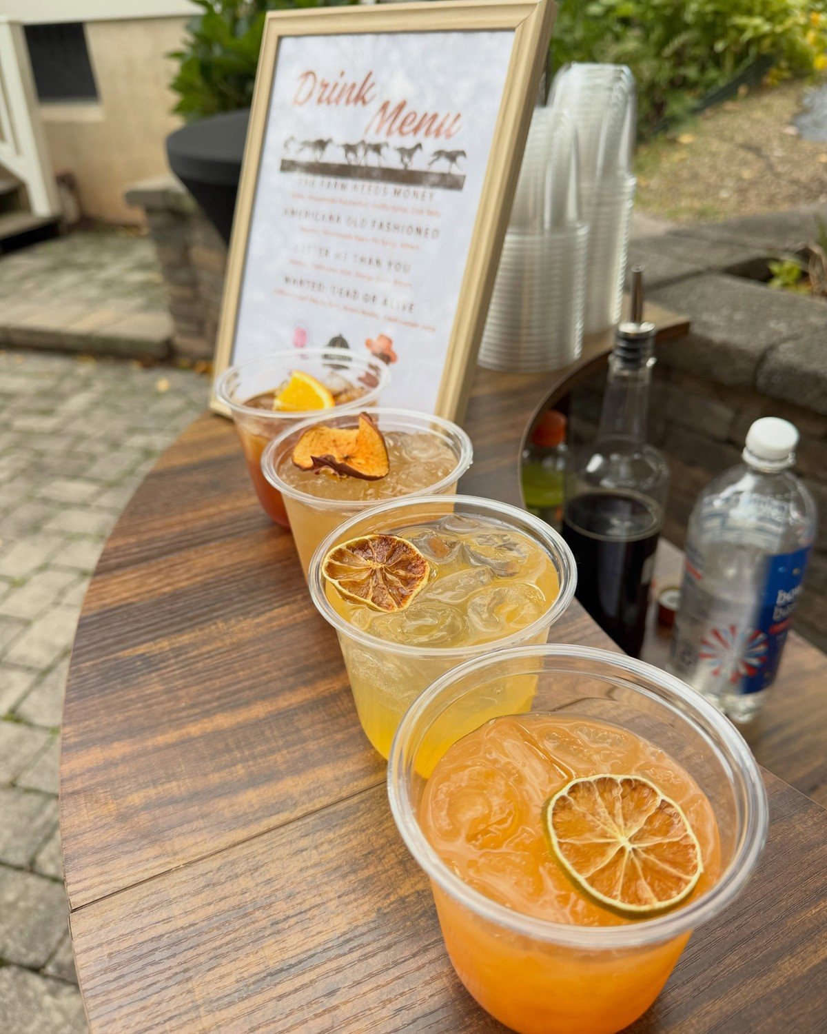 Four Compass Mobile Bar cocktails with citrus garnishes lined up on the wooden bar at a Far Hills after party
