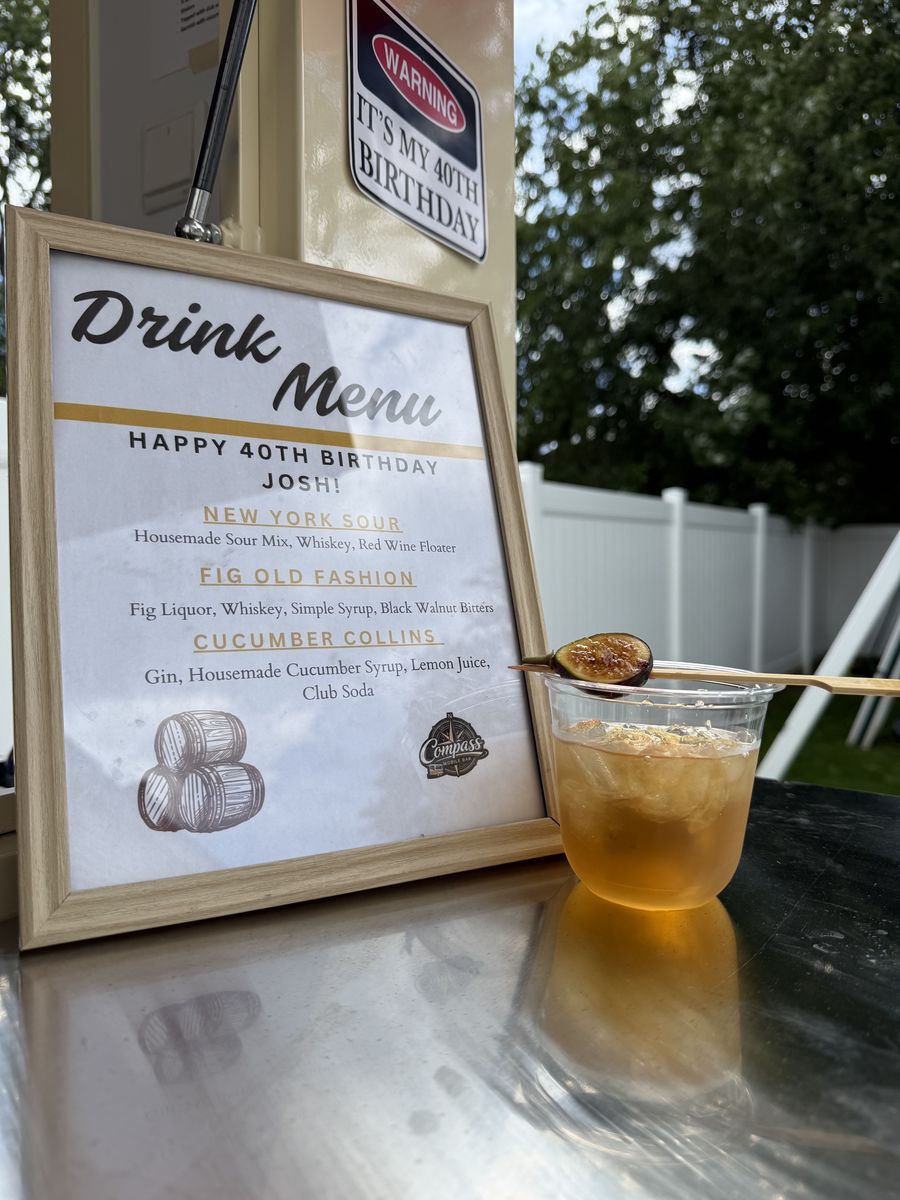 Fig Old Fashioned cocktail with a torched fig garnish in front of the birthday menu