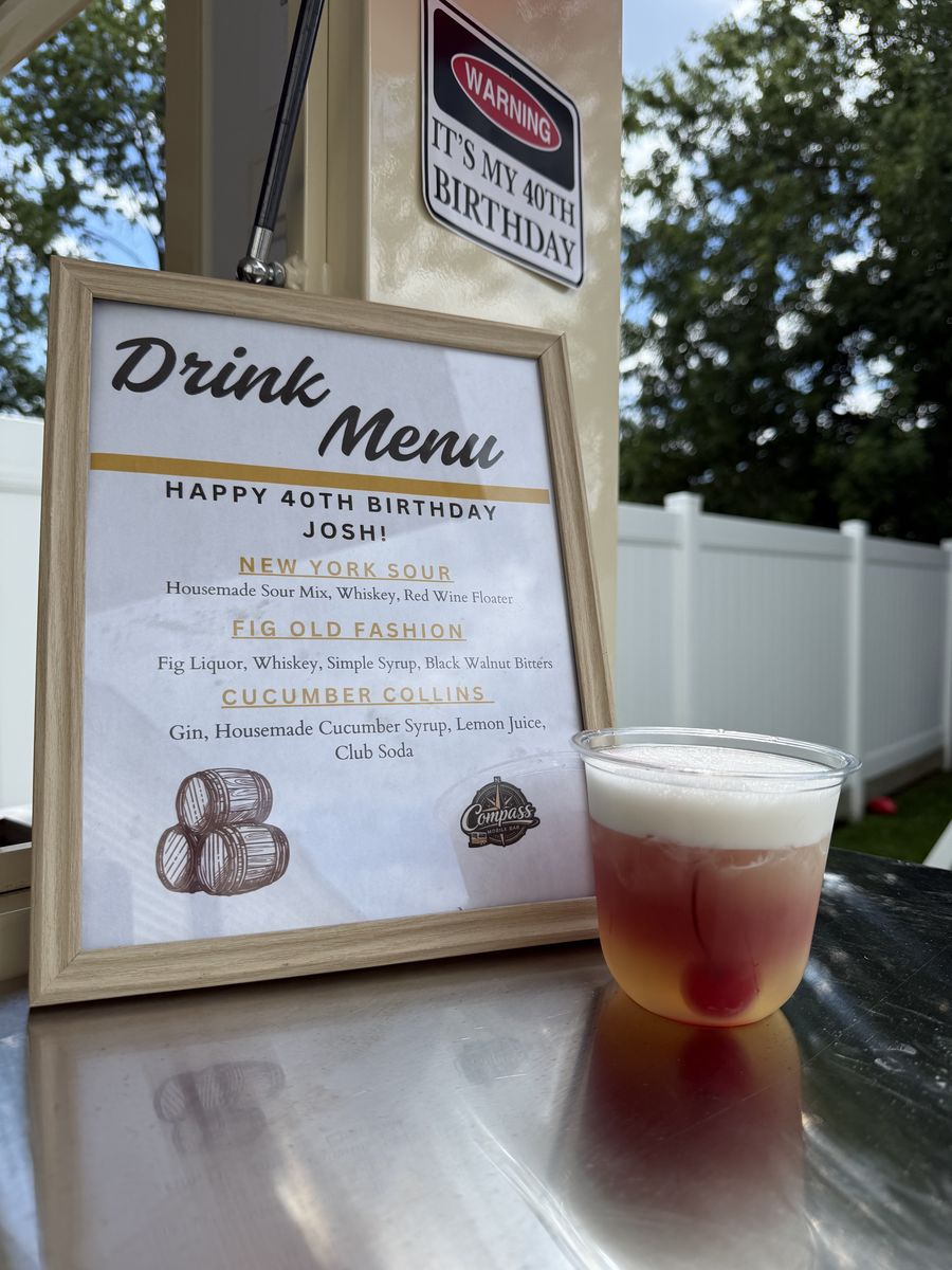 New York Sour cocktail with a layered red wine floater beside the birthday drink menu