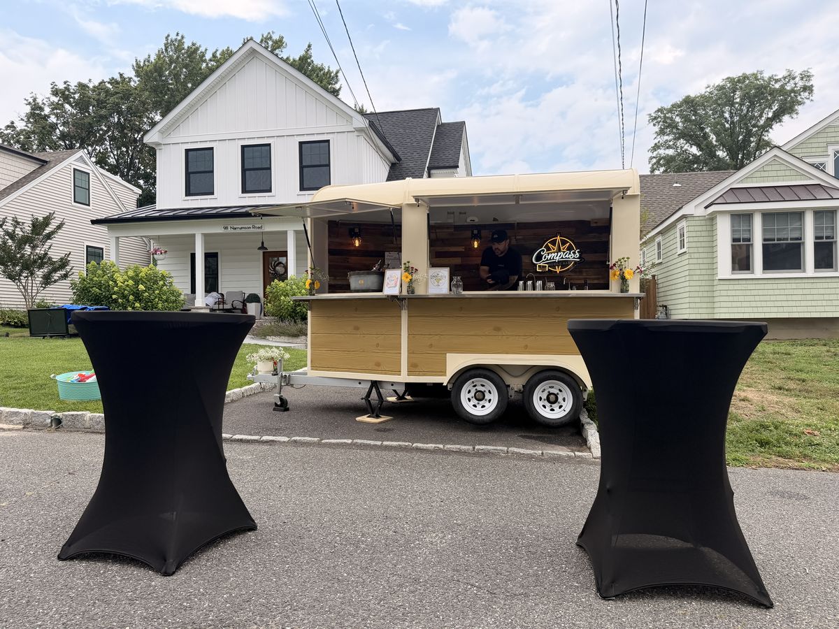 High top tables and guests near the Compass trailer at the Manasquan block party