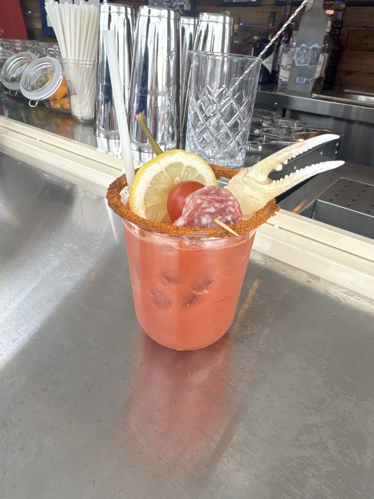 Close up of the Crab Legs And Football Bloody Mary with a crab leg, lemon, and salami garnish