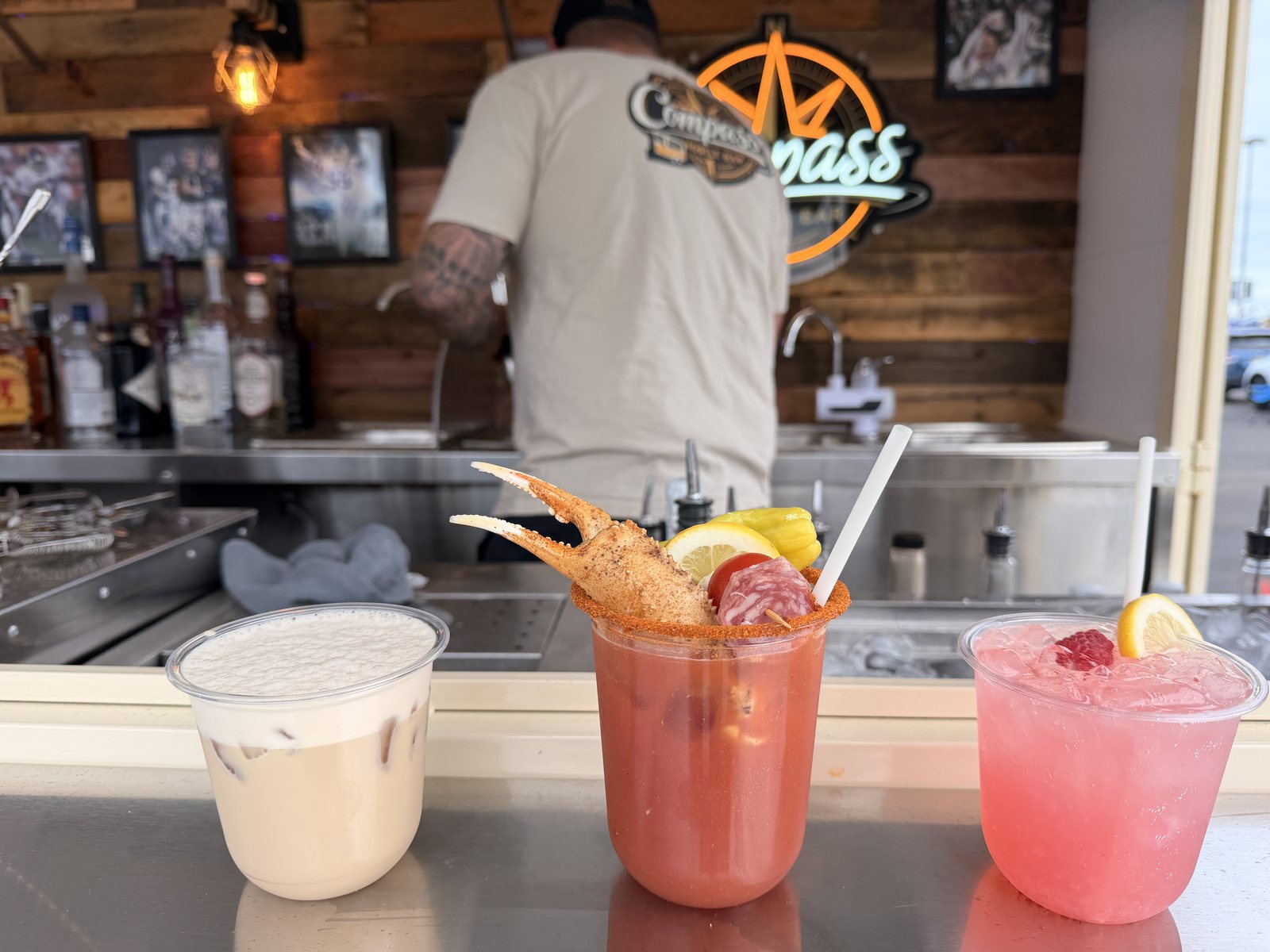 The three gameday drinks lined up on the Compass bar top: Kickoff Latte, Crab Legs And Football, and the Big Blue Refresher