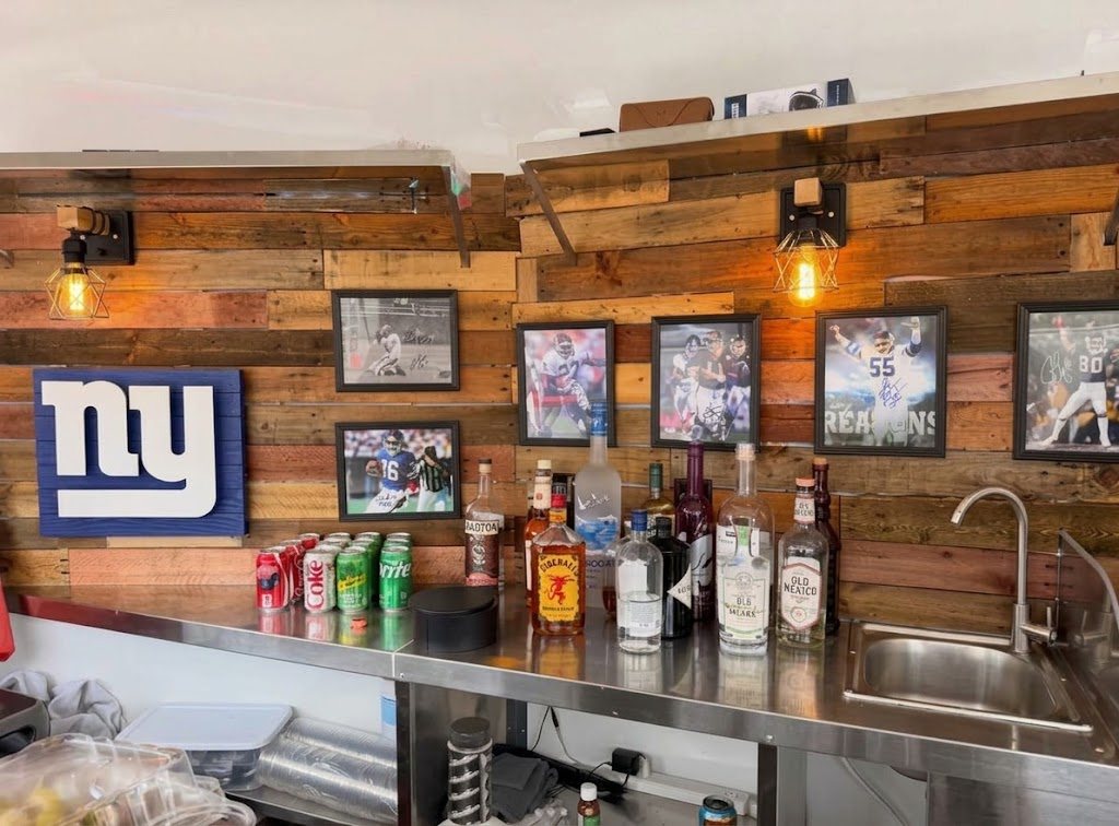 The gameday drink menu beside a Bloody Mary garnished with a crab leg at the Compass trailer