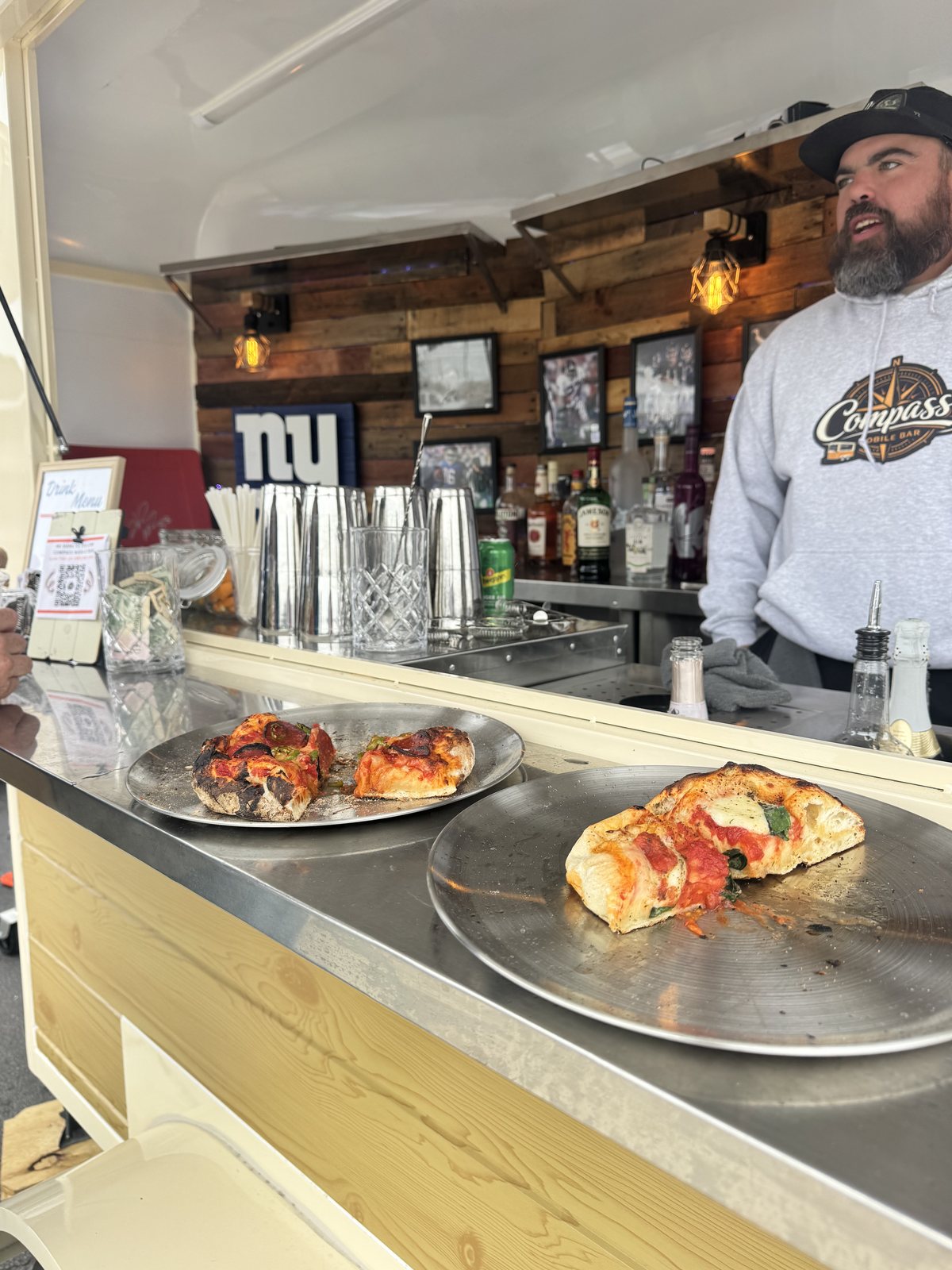 Slices of pizza on plates on the Compass bar top during the tailgate
