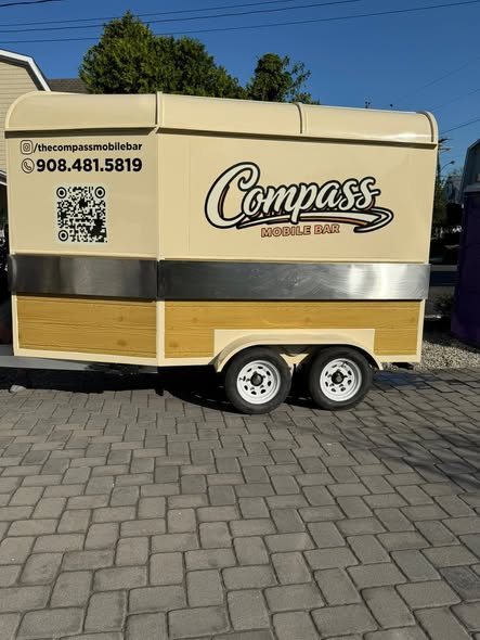 Side of the Compass trailer with the logo, phone number, and booking QR code
