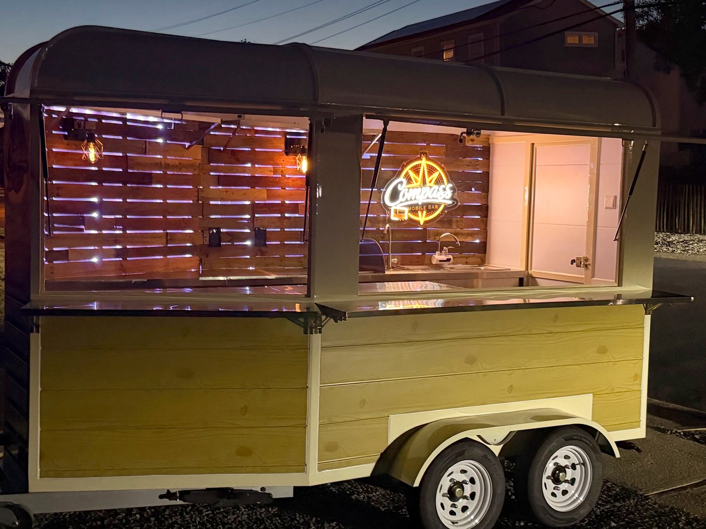 The trailer glowing at dusk with the neon Compass sign on