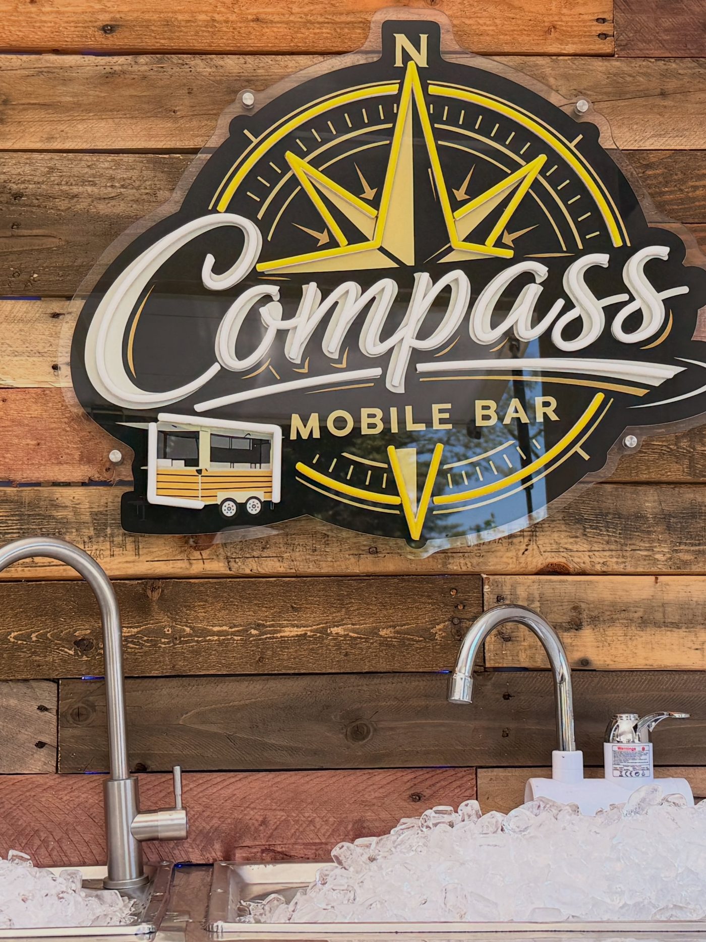 Compass sign mounted on the reclaimed wood backbar
