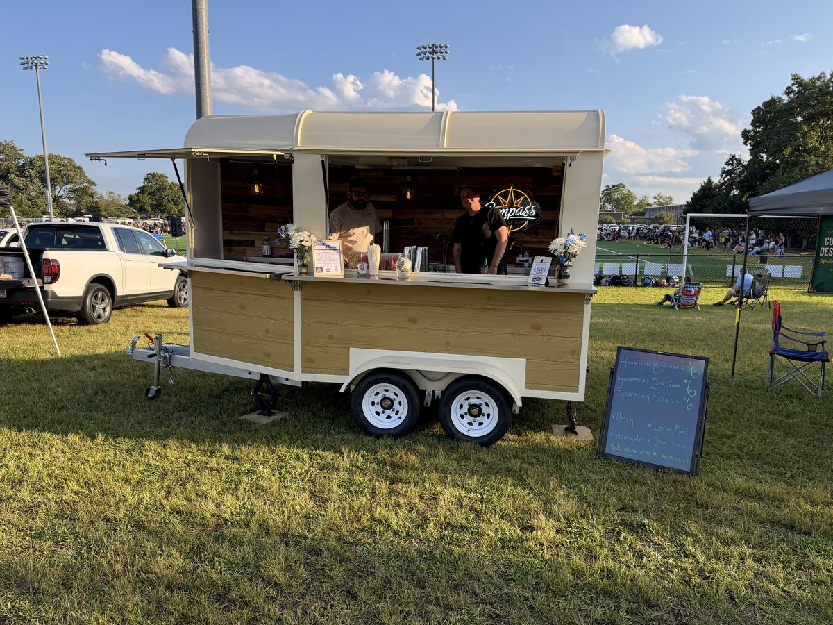 The Compass trailer serving housemade lemonade and sodas beside the turf field at the Warriors pep rally